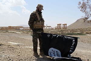 A member of the Syrian pro-government forces carries an Islamic State flag