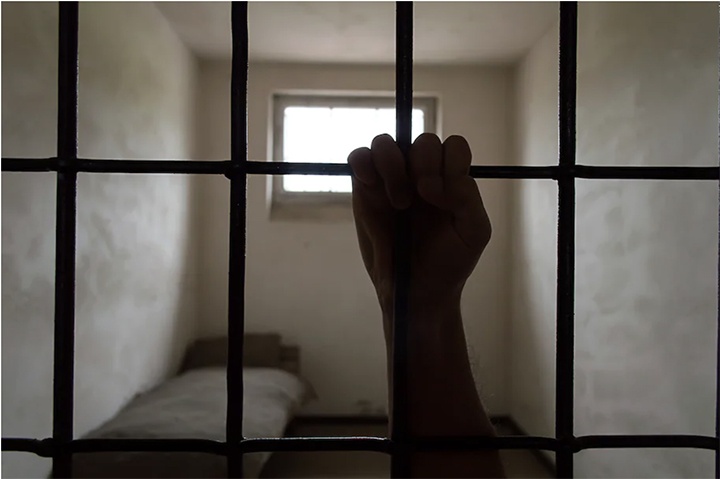 Profile of a hand in front of jail cell