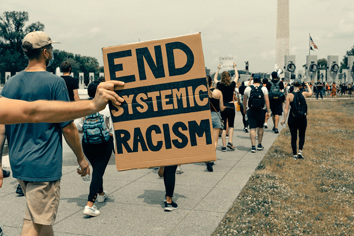 people marching, sign reads end systemic racism