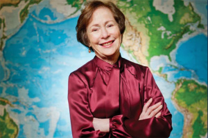Suzanne Berger smiling at the camera in front of a giant map background